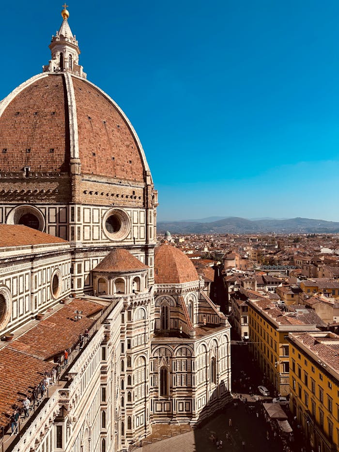 A stunning aerial view of Florence's iconic cathedral and the surrounding cityscape under a clear blue sky.